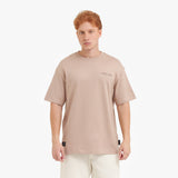 A male model with red hair wearing a beige oversized t-shirt, shown from the chest up.