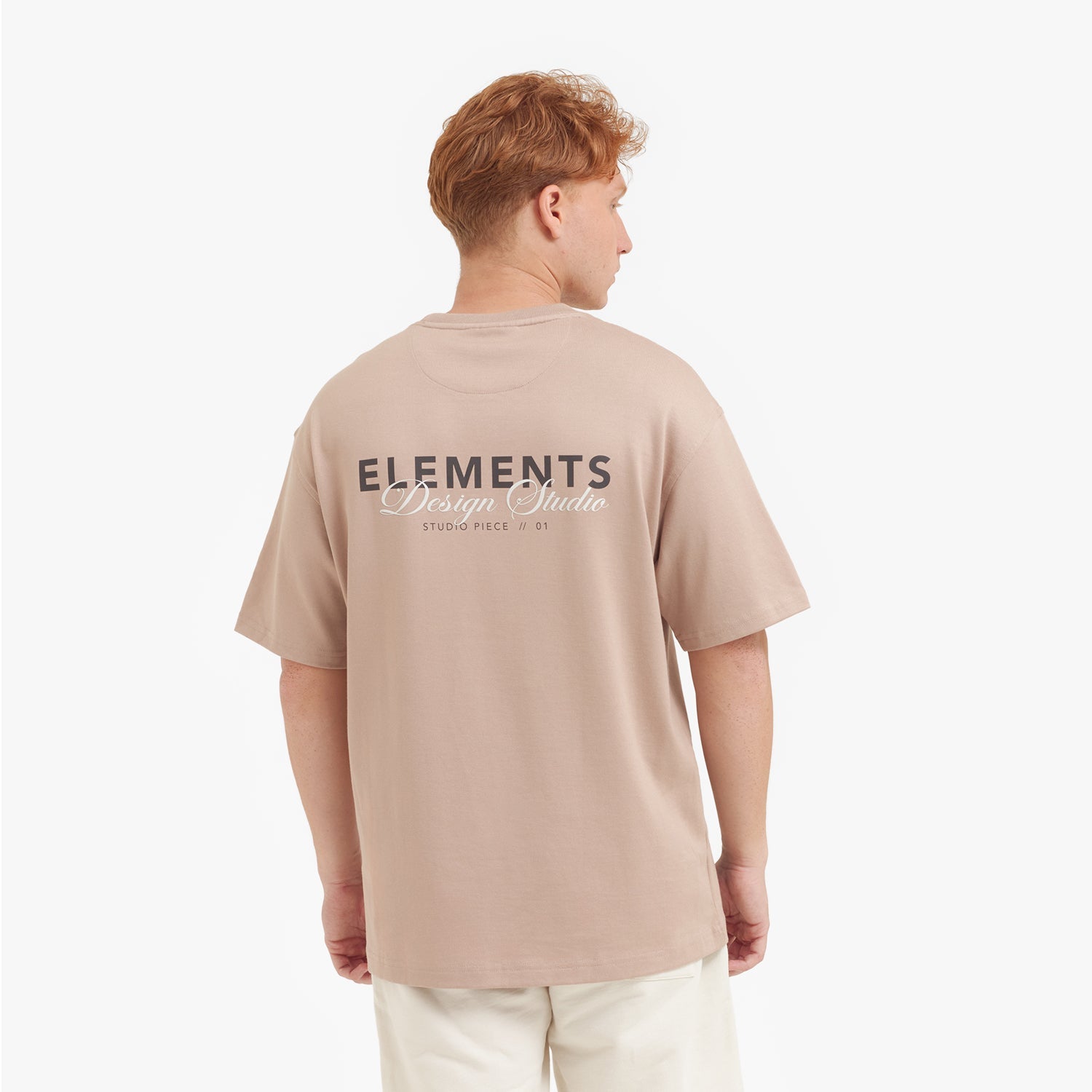 Male model showing the back of the beige t-shirt with the "ELEMENTS Design Studio" graphic