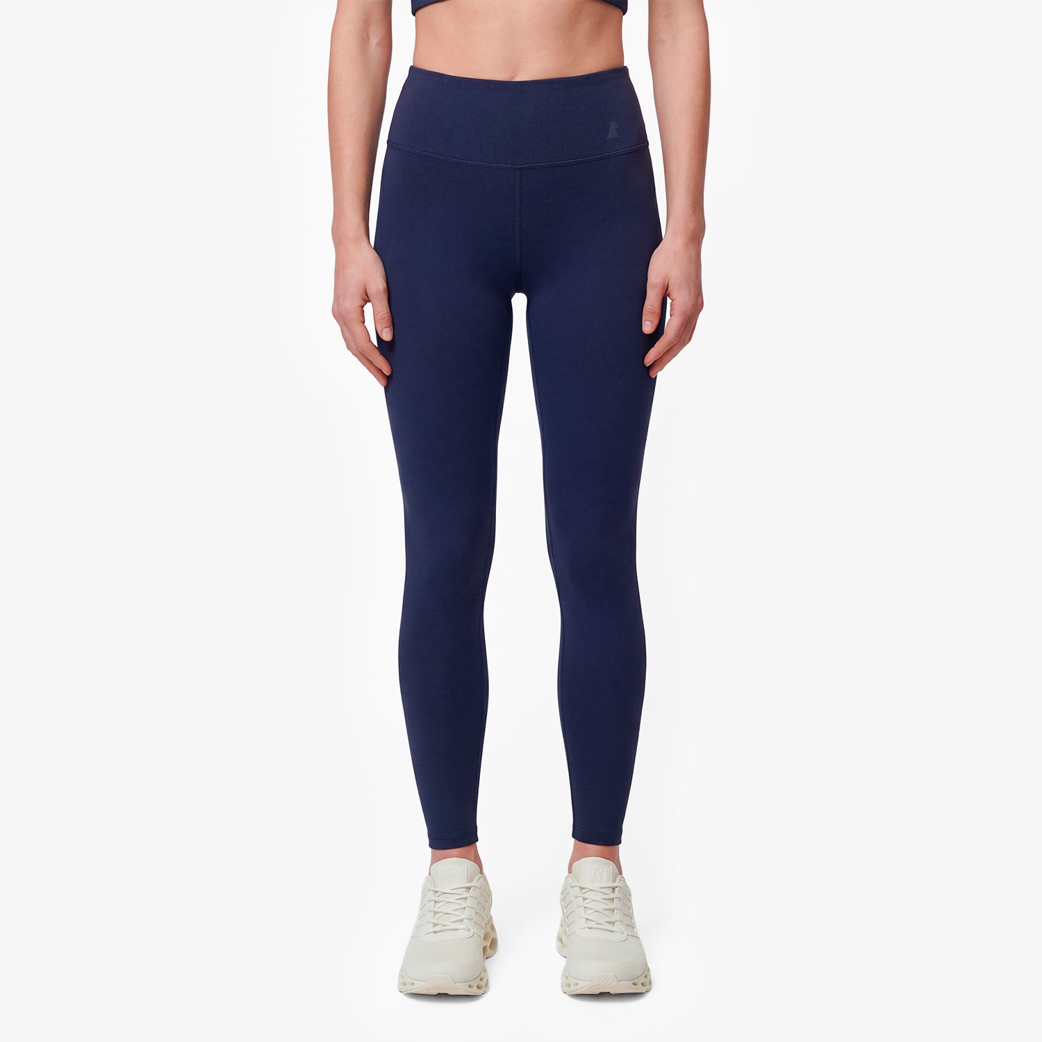 Person wearing navy blue leggings on a white background