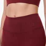 Maroon athletic top and leggings with a brand logo on a white background