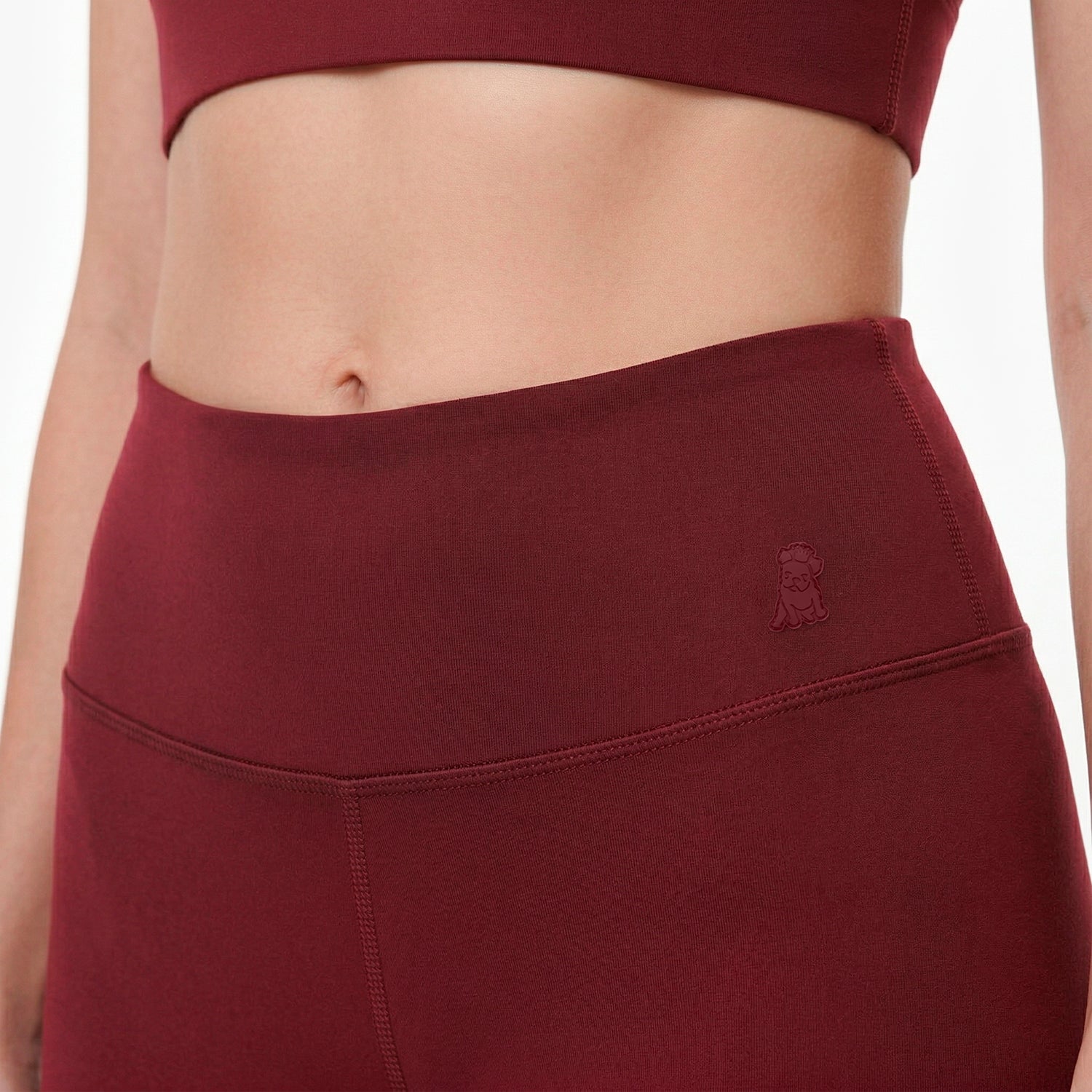Maroon athletic top and leggings with a brand logo on a white background