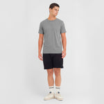 Man wearing a gray t-shirt and black shorts on a white background