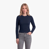 Woman wearing a navy long-sleeve top and gray jeans on a white background