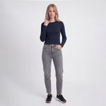 Woman wearing a navy long-sleeve top and gray jeans on a white background