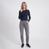 Woman wearing a navy long-sleeve top and gray jeans on a white background