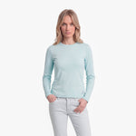 Woman wearing a light blue long-sleeve shirt and white pants on a white background