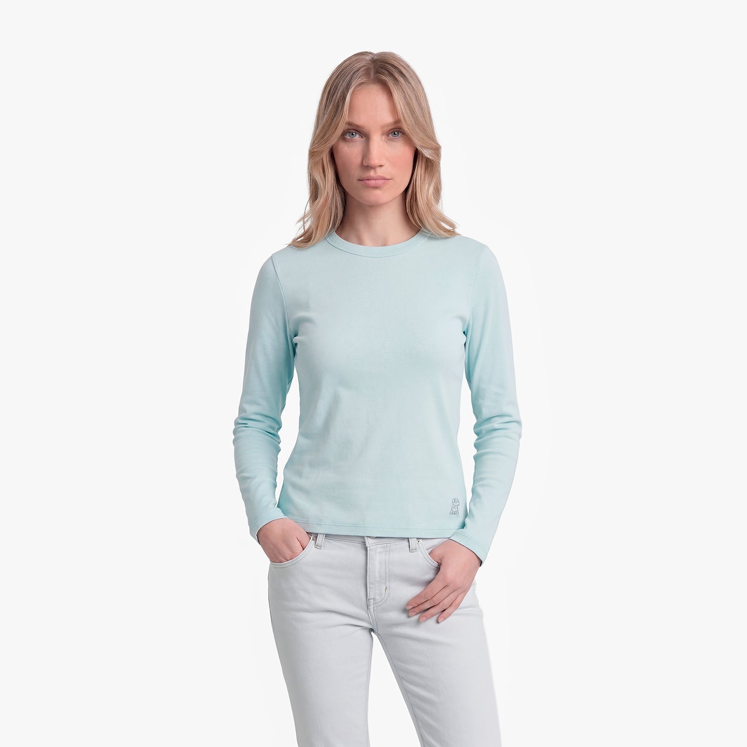Woman wearing a light blue long-sleeve shirt and white pants on a white background