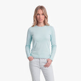 Woman wearing a light blue long-sleeve shirt and white pants on a white background