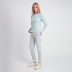Woman wearing a light blue long-sleeve top and light gray jeans on a white background