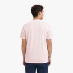 Back view of a man wearing a light pink t-shirt on a white background