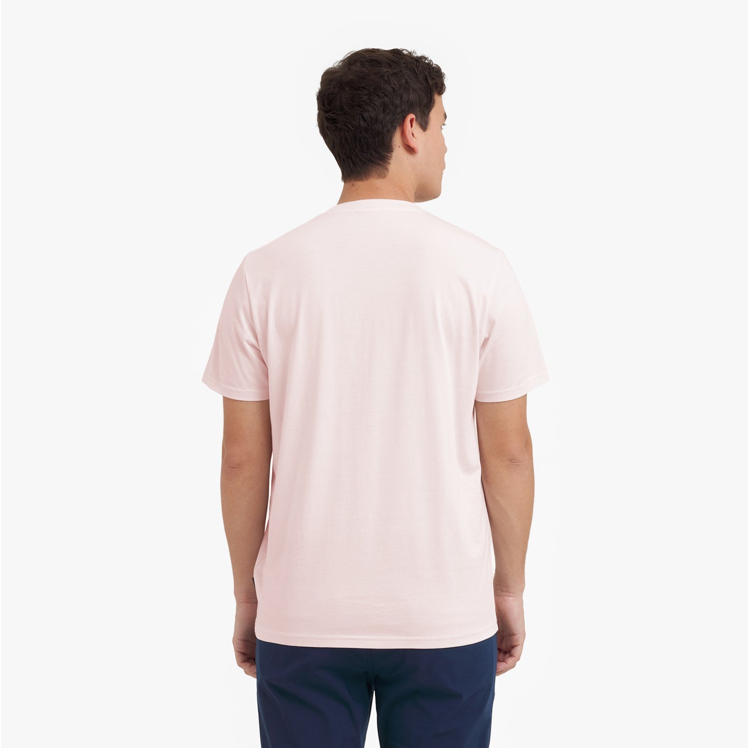 Back view of a man wearing a light pink t-shirt on a white background