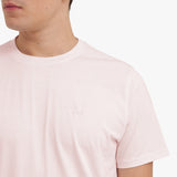 Close-up of a light pink t-shirt worn by a person on a white background