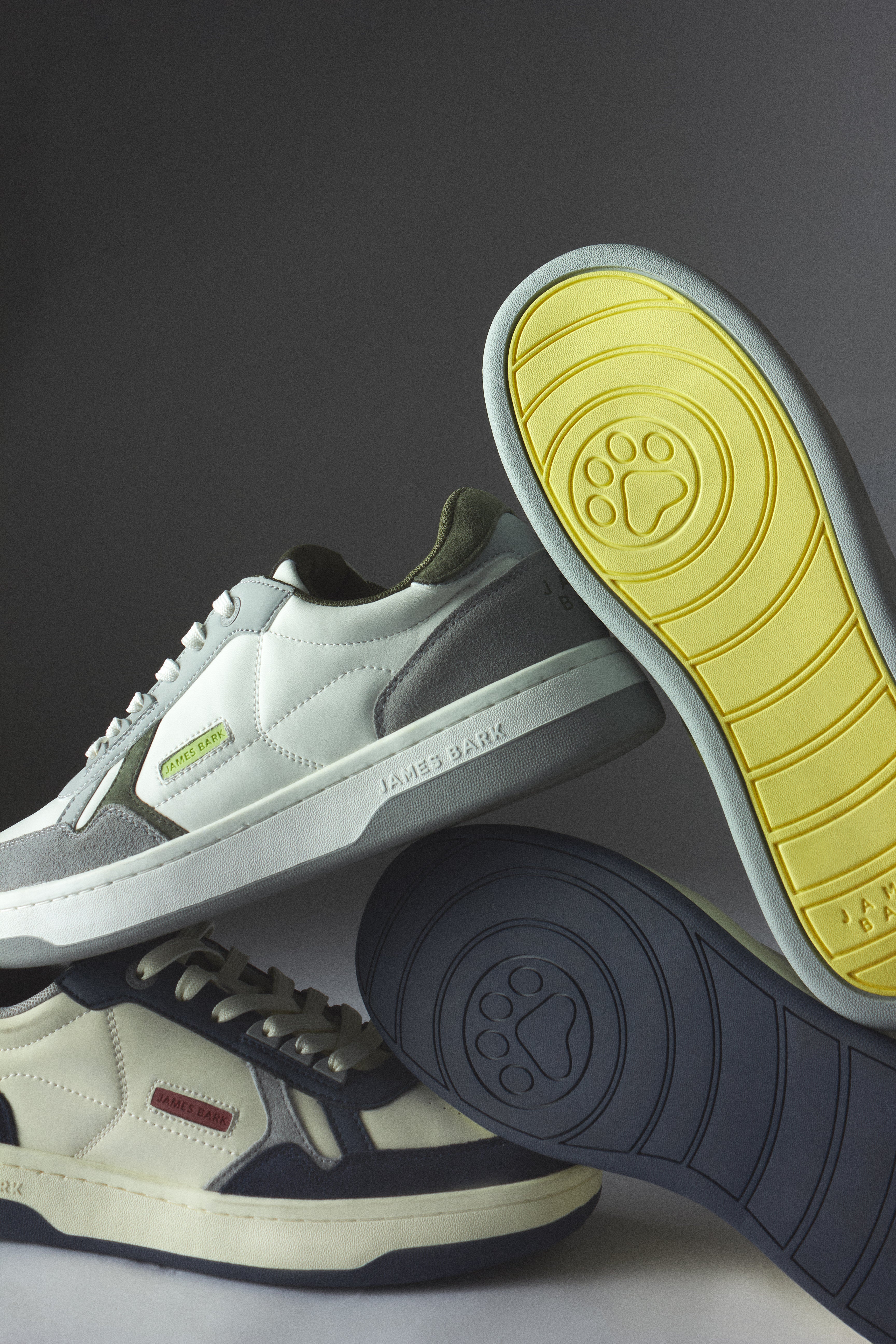Two pairs of sneakers with different colored soles on a dark background