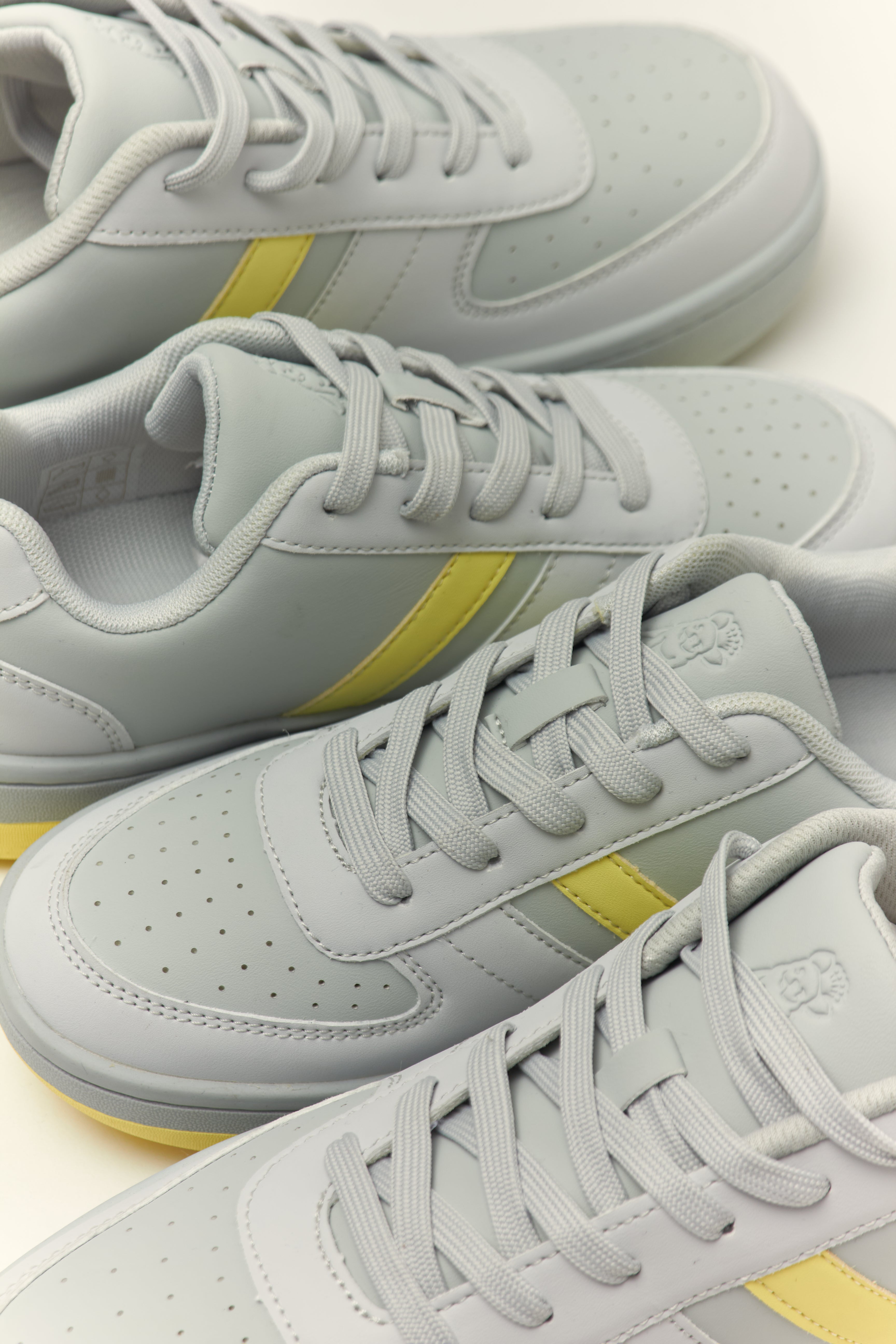 Gray sneakers with yellow accents on a light background