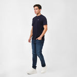 Man wearing a navy t-shirt and jeans on a white background