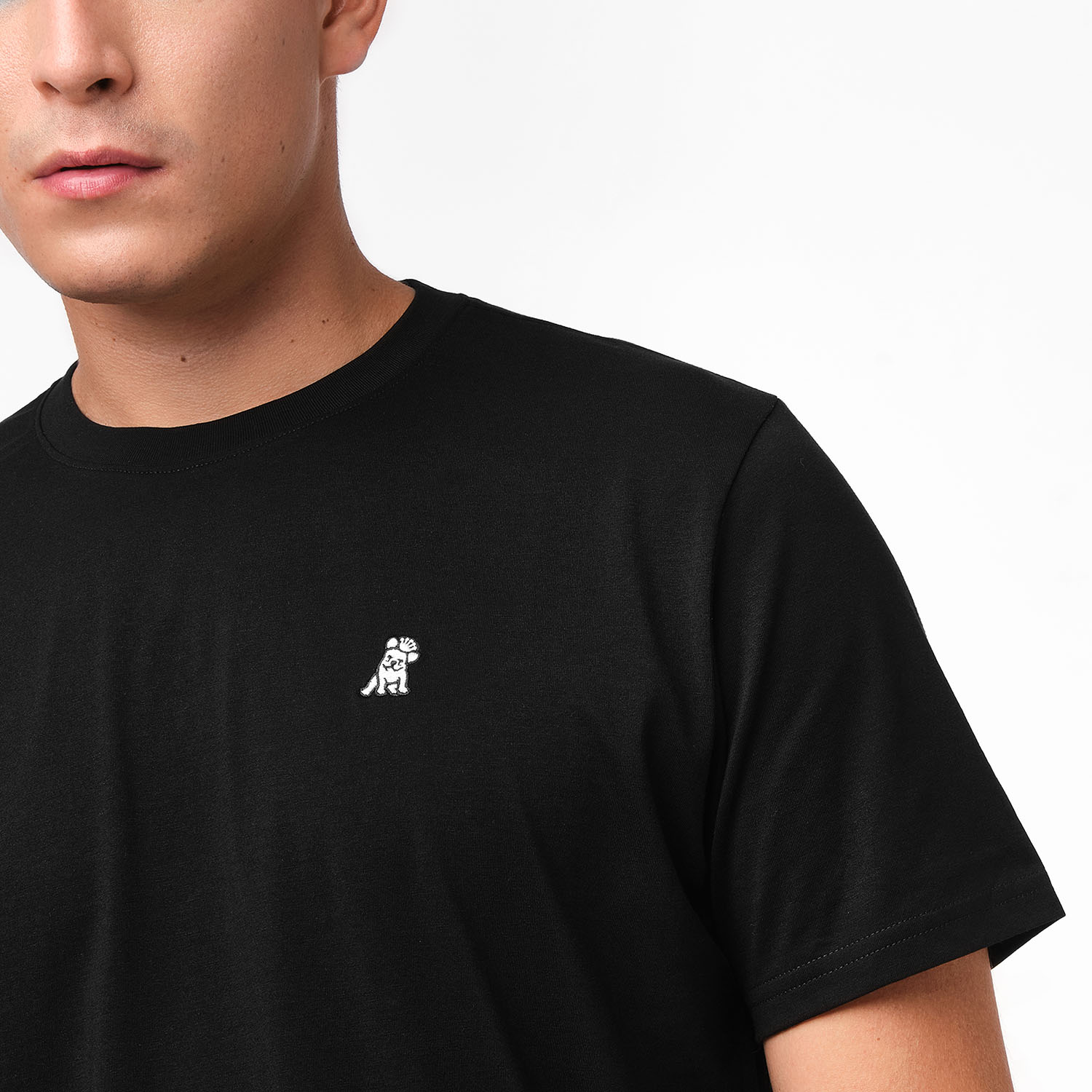 Black t-shirt with a small white logo worn by a person on a plain background