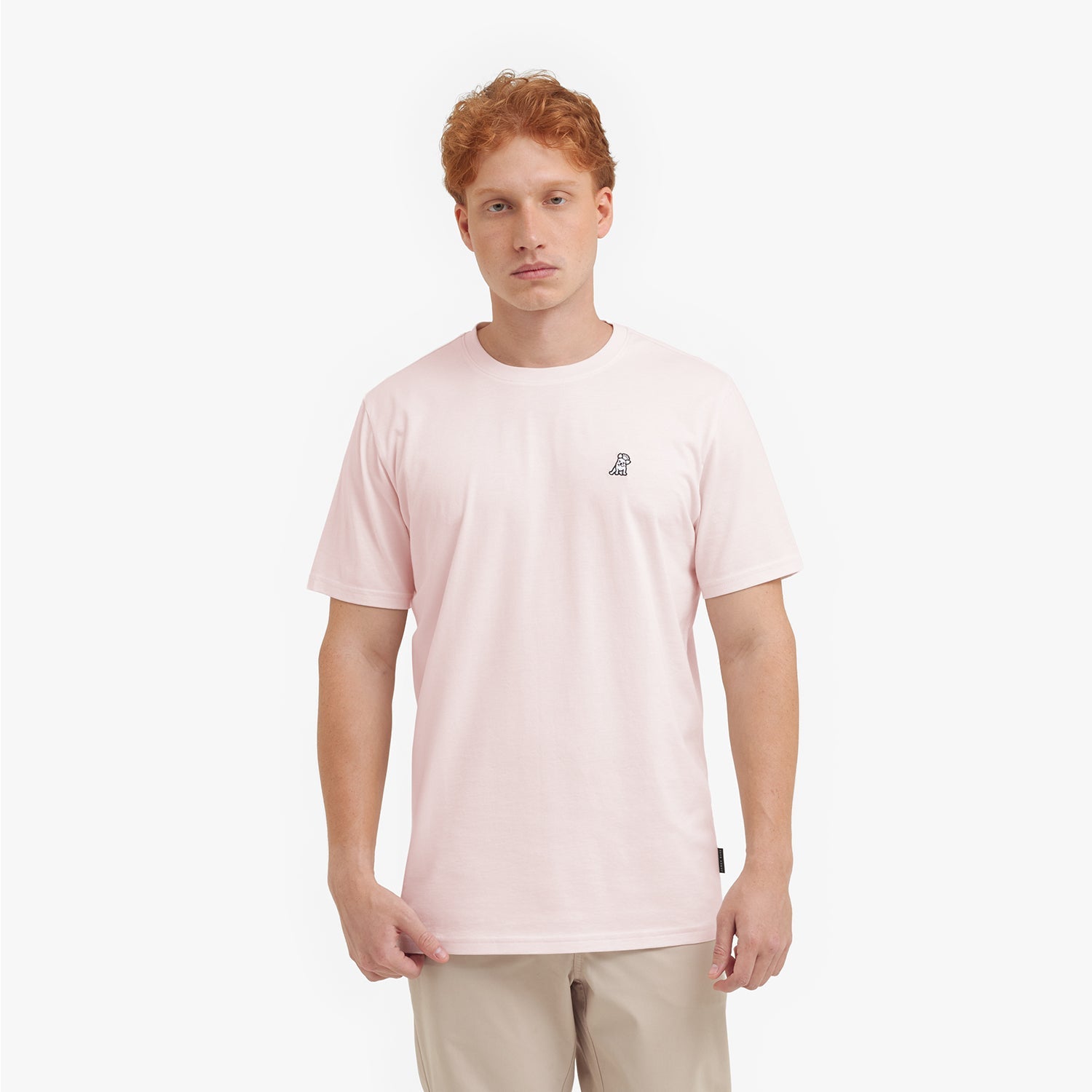 Man wearing a light pink t-shirt with a small logo on a white background