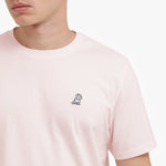 Close-up of a person wearing a light pink t-shirt with a small logo on the chest.