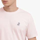 Close-up of a person wearing a light pink t-shirt with a small logo on the chest.