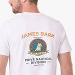 A man wearing a white T-shirt, viewed from the back. The shirt features a large graphic print with the text 'JAMES BARK' in orange, a circular crest with a dog illustration, and 'PRIVÉ NAUTICAL DIVISION' in dark blue text below.