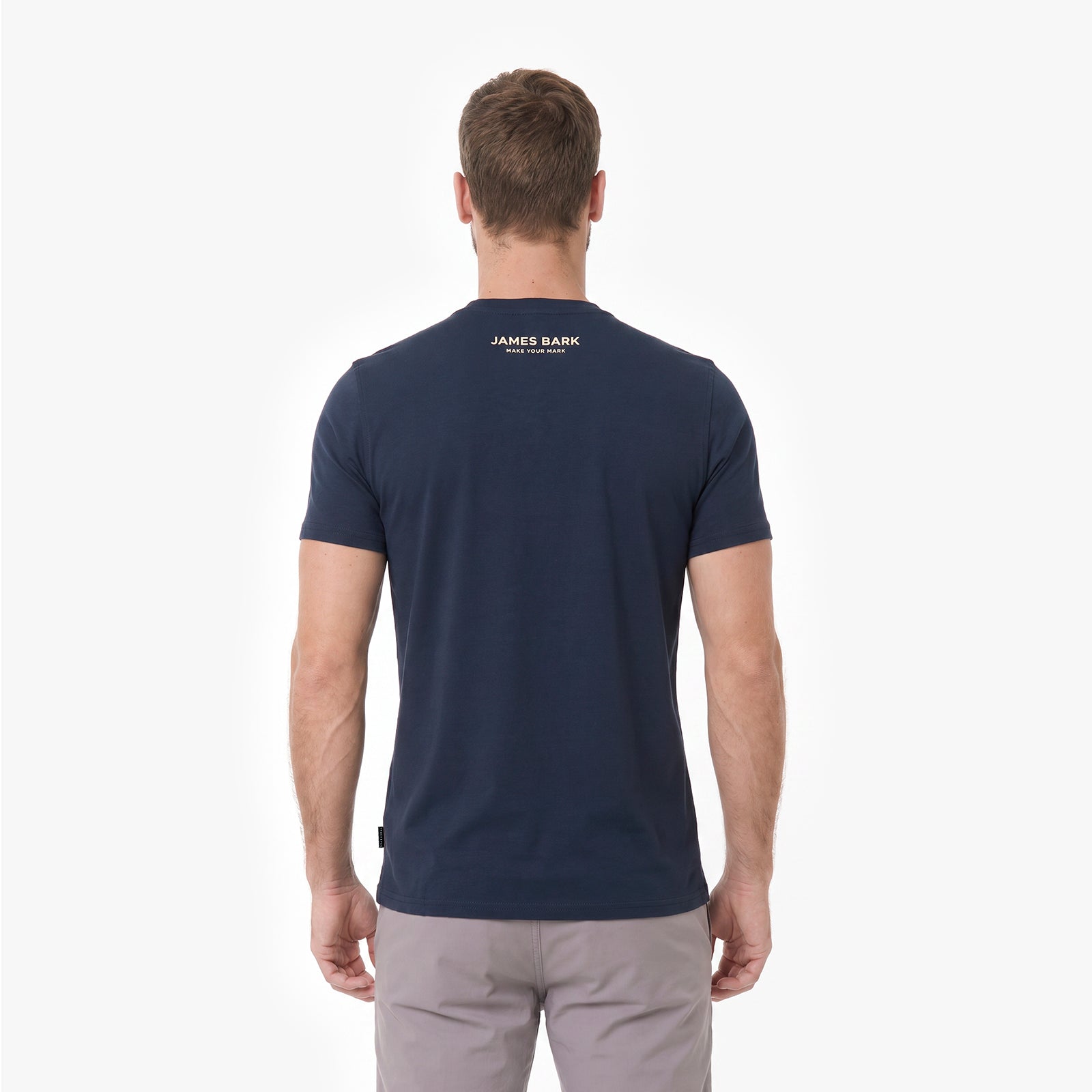 A man viewed from behind, wearing a navy blue T-shirt with 'JAMES BARK' printed in gold on the upper back