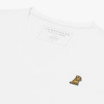 Angled close-up of the white v-neck t-shirt's neckline and chest, highlighting the inner printed label and the detailed yellow and black embroidered dog logo