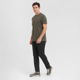 Man wearing a green t-shirt and black pants on a white background