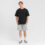 Man wearing a black t-shirt and gray shorts on a white background