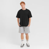 Man wearing a black t-shirt and gray shorts on a white background
