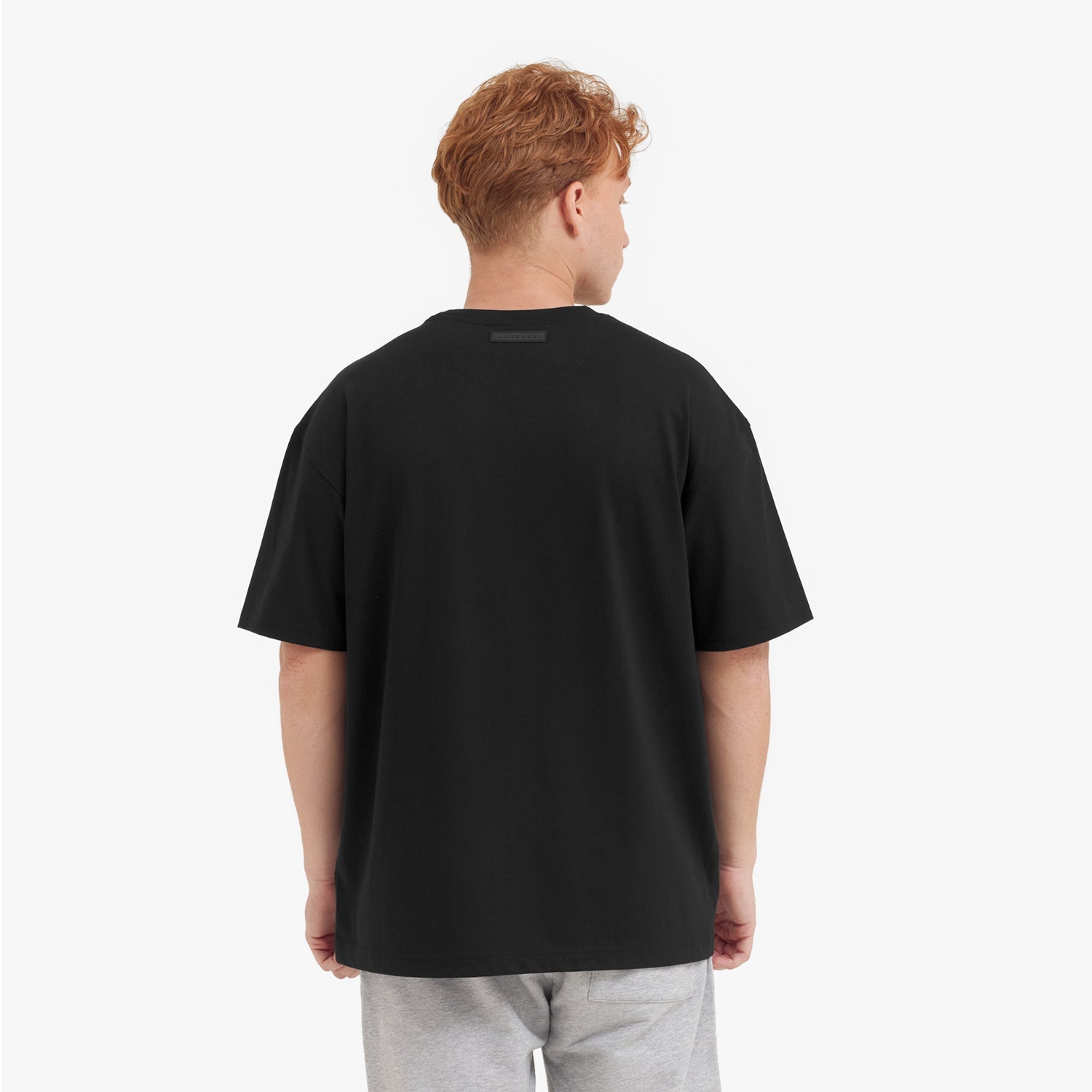 Back view of a man wearing a black t-shirt on a white background