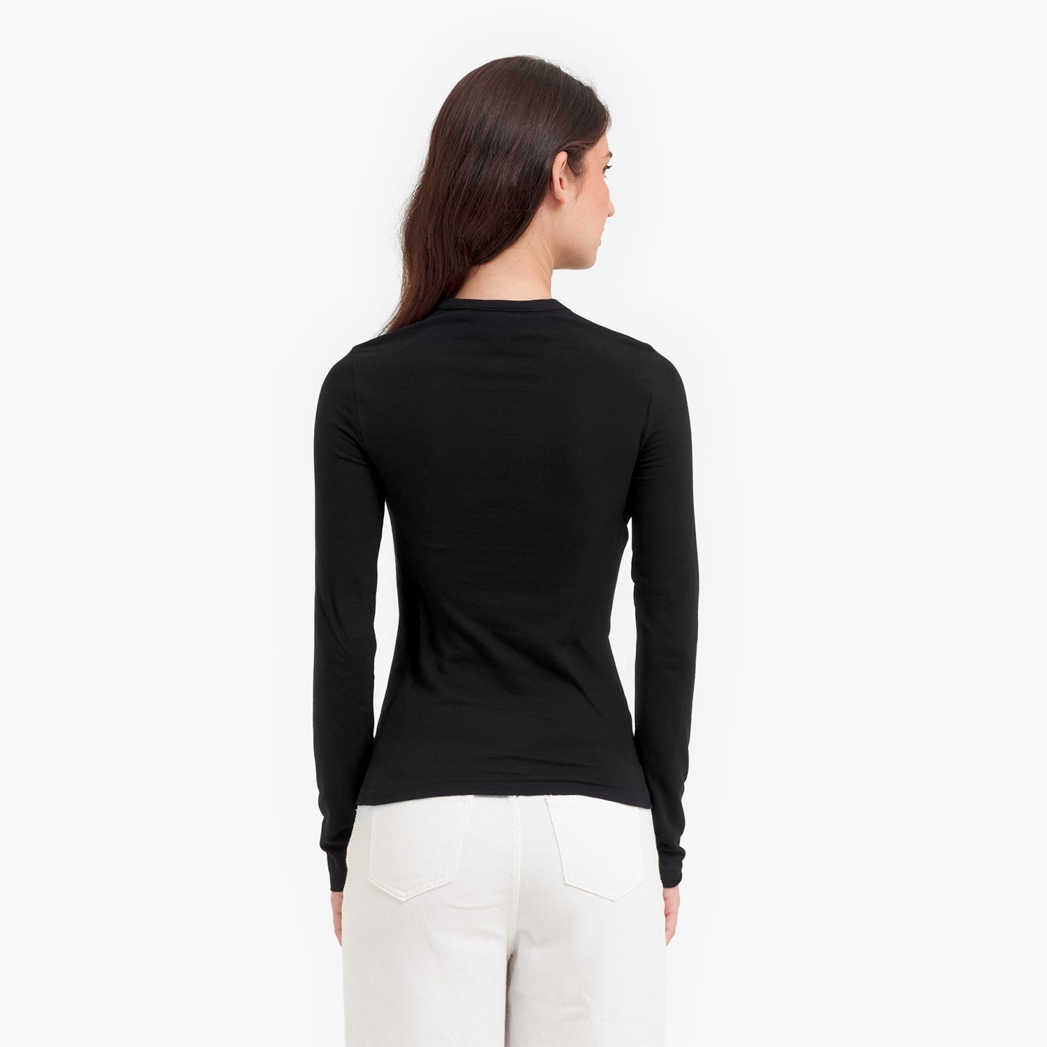 Back view of a woman wearing a black long-sleeve top and white pants on a white background