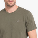 Man wearing a green t-shirt with a small logo on a white background