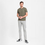 Man wearing a green t-shirt and gray pants on a white background