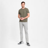 Man wearing a green t-shirt and gray pants on a white background