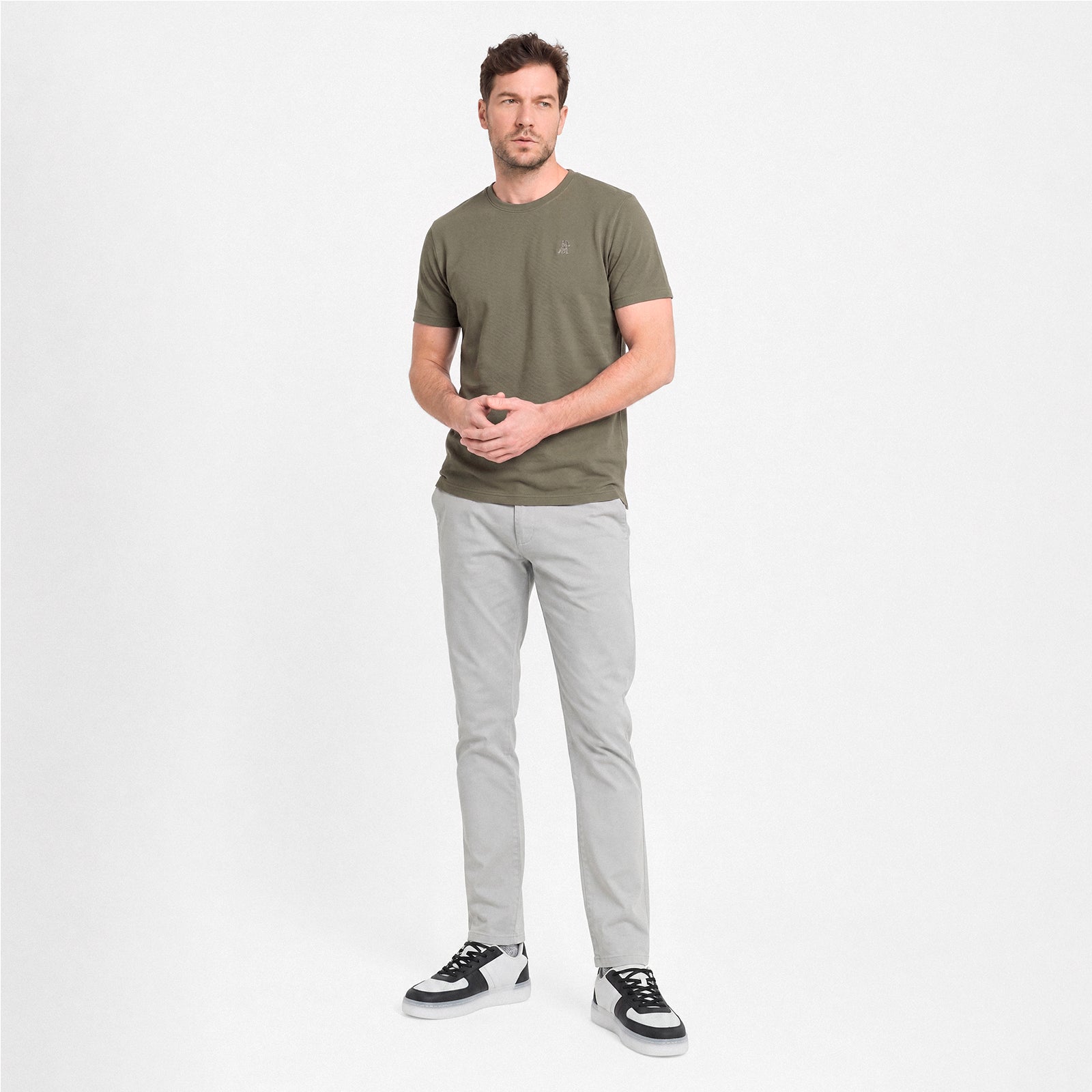 Man wearing a green t-shirt and gray pants on a white background