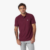 Man wearing a maroon polo shirt with a small logo on a white background