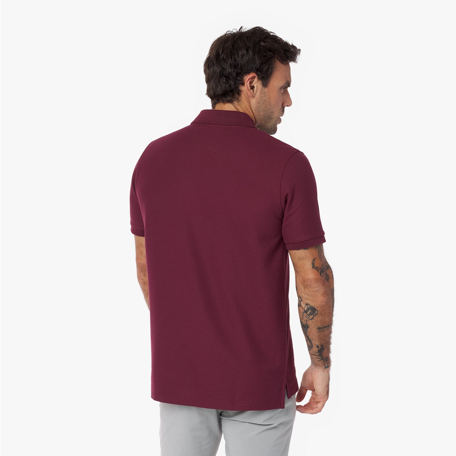 Back view of a man wearing a maroon polo shirt on a white background