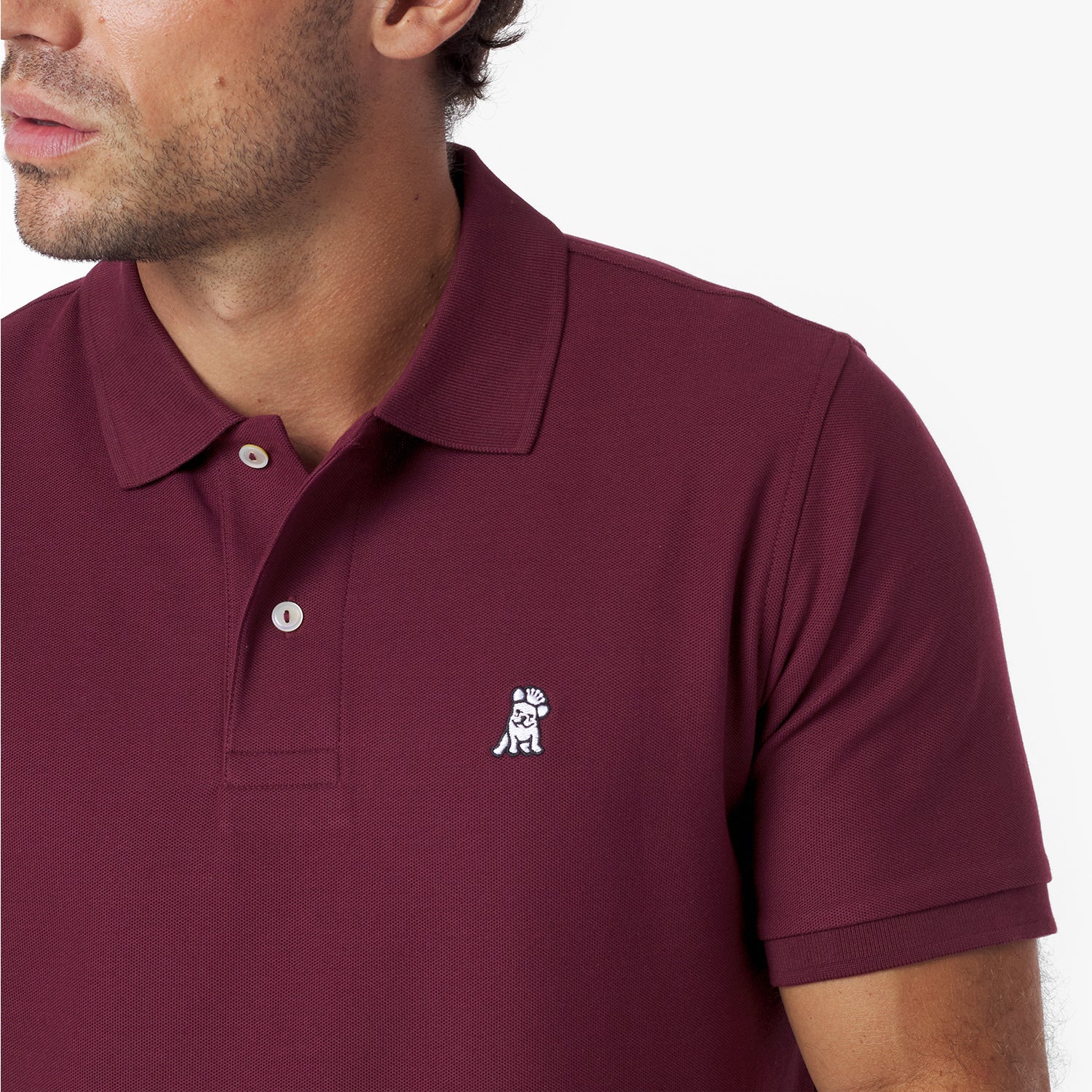 Close-up of a maroon polo shirt with a small logo on a white background