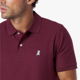 Close-up of a maroon polo shirt with a small logo on a white background