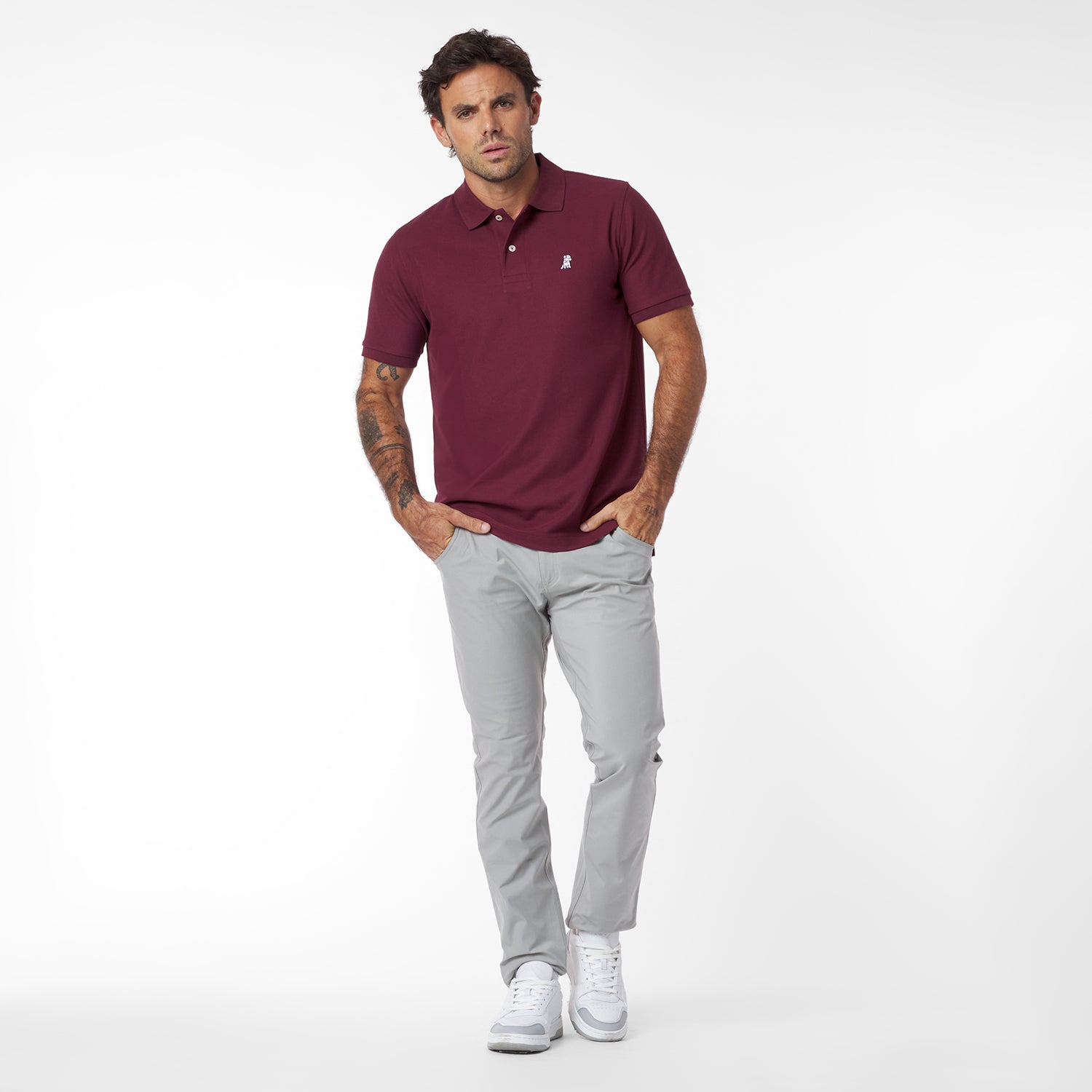 Man wearing a maroon polo shirt and gray pants on a white background