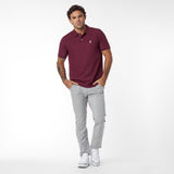 Man wearing a maroon polo shirt and gray pants on a white background