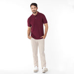 Man wearing a maroon polo shirt and beige pants on a white background