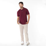 Man wearing a maroon polo shirt and beige pants on a white background