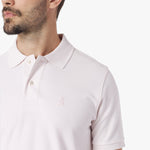 Close-up of a man wearing a light pink polo shirt on a white background