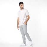 Man wearing a light pink t-shirt and light gray pants on a white background