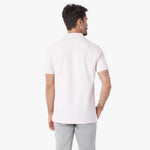 Back view of a man wearing a light pink polo shirt and light gray pants on a white background