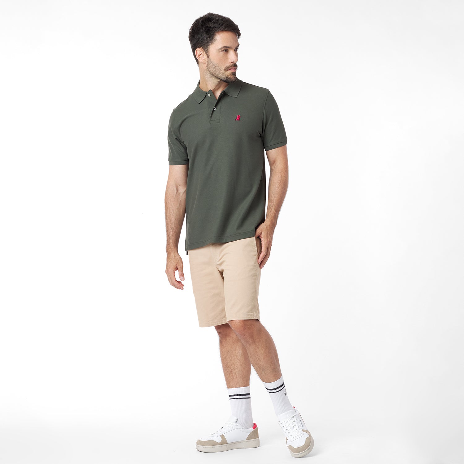 Full body view of a man wearing a green polo shirt with a red logo