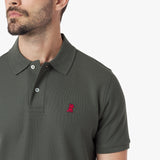 Close-up of a man wearing a green polo shirt with a red logo on a white background