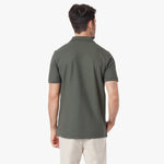 Back view of a man wearing a green polo shirt on a white background