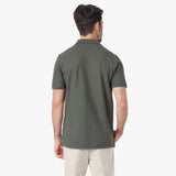 Back view of a man wearing a green polo shirt on a white background